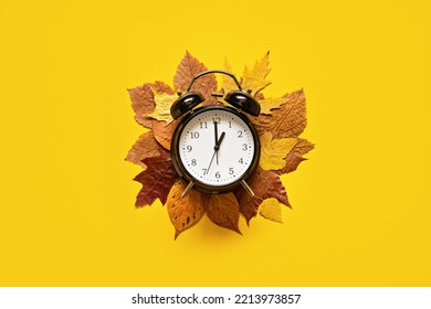 Daylight saving day. Fall Back. Black Alarm clock and autumn leaves on yellow background. Daylight saving time end - Shutterstock ID 2213973857