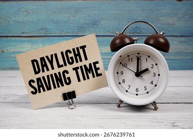 Daylight Saving Time  text written on paper card with alarm clock on wooden background