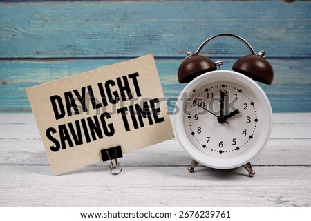 Daylight Saving Time  text written on paper card with alarm clock on wooden background