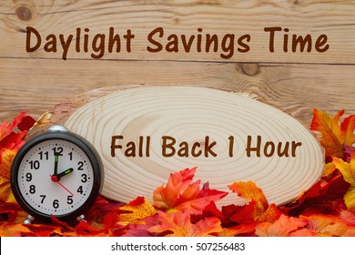 Daylight Savings Time Message, Some Fall Leaves, An Alarm Clock And Wood Plaque On Weathered Wood With Text Fall Back 1 Hour