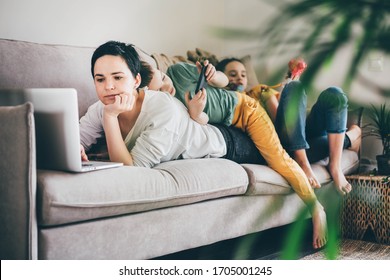 Daytime with family at home. Mother working from home, using laptop. Children playing games on a tablet and watching cartoons. - Powered by Shutterstock