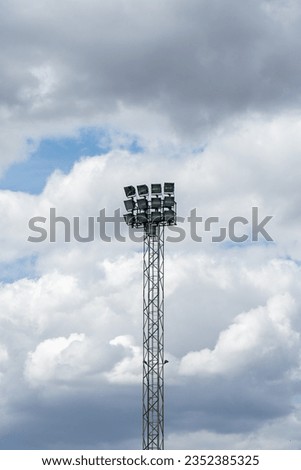Daytime shot of a football stadium's towering floodlight against a clear blue sky. Iconic sports venue vibe.