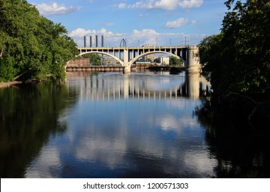 Daytime View Of The I-35W Bridge In Downtown Minneapolis With The Mississippi River In The Foreground. Summer