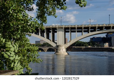 Daytime View Of The I-35W Bridge In Downtown Minneapolis With The Mississippi River In The Foreground. Summer