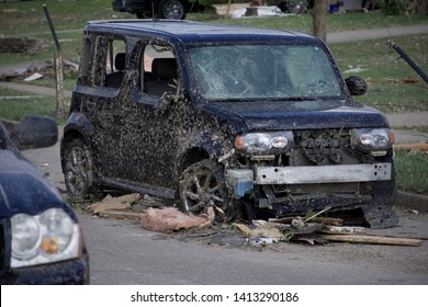 Dayton, OH; May 28, 2019- Car Destroyed By Tornado In Beavercreek Ohio. Blown In Insulation, Flat Tires, Missing Bumper, And Broken Windows Are Visible. Debris Surrounds The Vehicle On The Road.