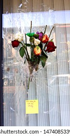 Dayton, Ohio / United States - August 7 2019: A bouquet covers a bullet hole in an Oregon District window after nine people were murdered and dozens injured in a mass shooting