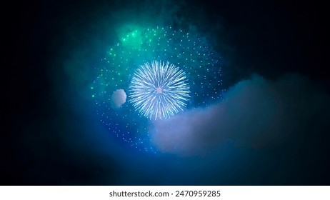 A dazzling display of fireworks explodes in a night sky. The fireworks are multicolored, with bursts of red, green, blue, yellow, and orange. Smoke trails from the fireworks linger in the air. - Powered by Shutterstock
