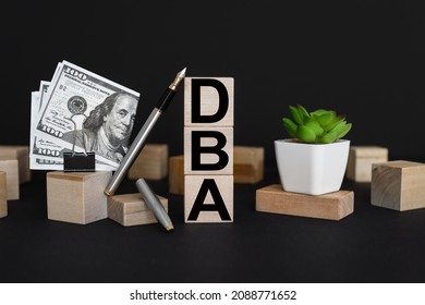 DBA. Side view of three empty wooden cubes isolated on a black background. Place for your text. business concept. pen and money