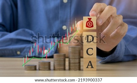 DCA word on a wooden cube and man hands holding money icon on wooden cude.Saving Coins, Saving Money.Dollar Cost Averaging.