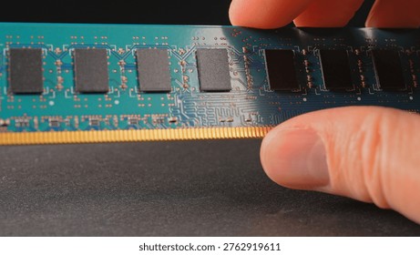 DDR RAM memory chips module macro view. Hand holding Random Access Memory RAM module disconnected from computer motherboard. Manufacturers redirect capacity production for AI data centers processing. 
