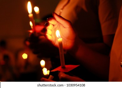 De Focused Candlelight With People. Bokeh Of Light Candle,Crowds Gather To Do Candlelight Activities. Closeup Of People Holding Candle Vigil In Darkness Expressing And Seeking Hope.