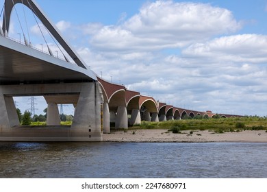 De Oversteek bridge seen from the water. River Maas waterfront shore of historic Hanseatic city Nijmegen - Shutterstock ID 2247680971