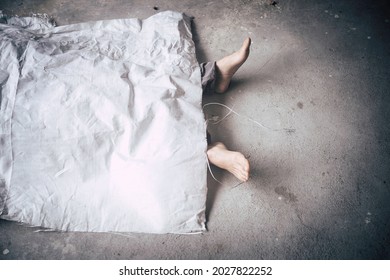 Dead body was cover by white sack, foot showing out of cover , half body of death on concret floor with dark tone and copy space.