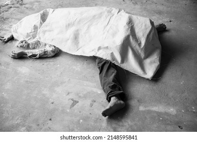 Dead body laying down unnaturally on concreate floor, was cover by sag, one leg with bare feet out of cover, crime scene, murder and violence concept.