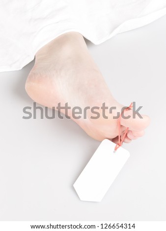 Dead body with toe tag, under a white sheet