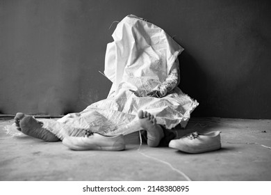 Dead body woman in sitting position againt the wall, murdered woman with bare foot was cover by sag, blur shoe at front in black and white tone.