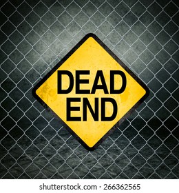 Dead End Grunge Yellow Warning Sign on Chain link Fence of Industrial Warehouse