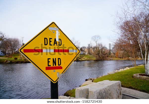 Dead End Road Sign at\
the end of a road that ends at the shore line of Rock River in\
Mayville, Wisconsin. 