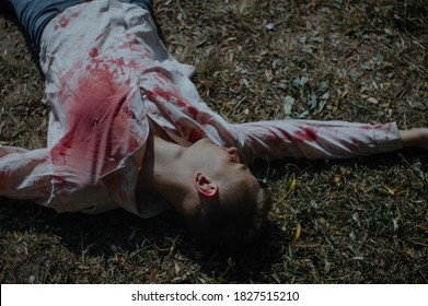 Dead Man Body Lying On The Ground In A Bloody Shirt