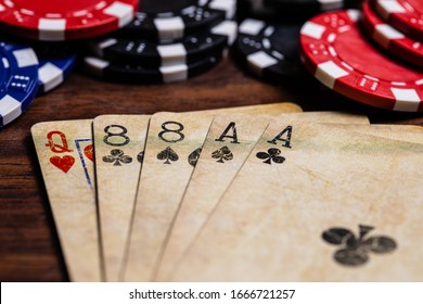 Dead Mans Hand with a well used vintage deck of cards on a dark hardwood surface with Red, Black and Blue Clay Chips present. Soft Warm color tone and space for Copy in the foreground on the cards