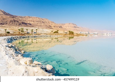 Dead Sea coastline with white salt beach and mountains at sunny day in Ein Bokek, Israel. White mineral salt shore at Dead sea, Israel. Dead sea landscape of Israel. Mineral water of Dead sea, Israel