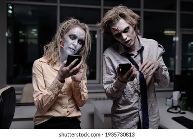 Empresarios muertos y espeluznantes con pintura de grasa zombi en sus caras y manos usando teléfonos inteligentes