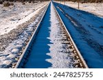 Dead straight single track railway line covered in snow on a frosty cold winter morning. Railroad track before passing of the first train from Williams to Grand Canyon Village with low morning sun