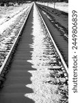Dead straight single track railway line covered in snow on a frosty cold winter morning. Railroad track before passing of the first train from Williams to Grand Canyon Village. Black and white.