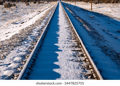 Dead straight single track railway line covered in snow on a frosty cold winter morning. Railroad track before passing of the first train from Williams to Grand Canyon Village with low morning sun - Powered by Shutterstock