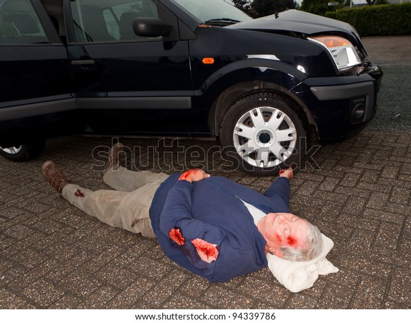 Dead or\
unconscious man lying next to a wrecked\
car