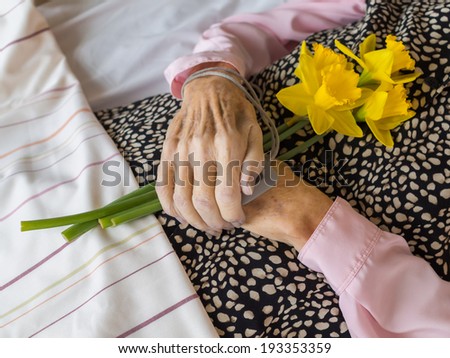A dead woman with her hands folded on the stomach, holding daffodils