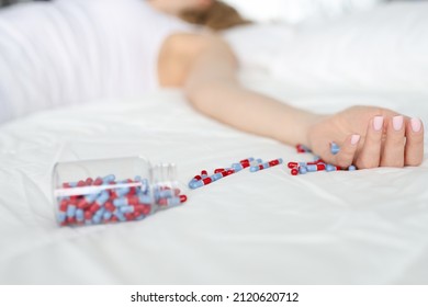 Dead Woman Lying On Bed With Scattered Medical Capsules Closeup