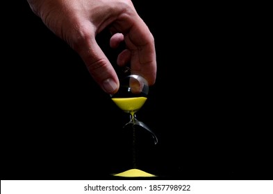Deadline Concept Broken Hourglass with Yellow Sand on Black Background