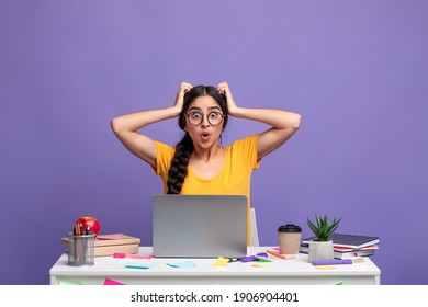 Deadline Concept. Portrait Of Shocked Surprised Indian Woman Sitting At Desk With Laptop Computer And Grabbing Her Head Isolated Over Purple Studio Background Wall. Stressed Lady At Workplace