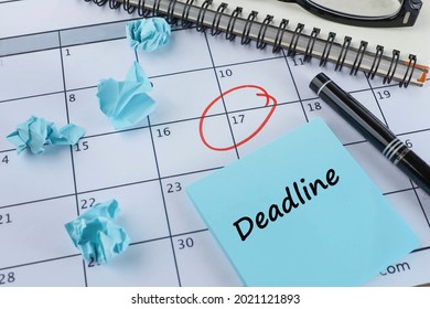 Deadline concept with Deadline text on the notepad, pen, red circle on the calendar, crumpled papers and notebook.   