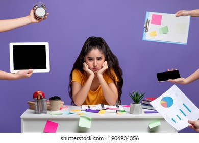 Deadline And Multitask Concept. Portrait Of Tired Sad Indian Woman Stressed By A Lot Of Work, Sitting At The Desk, Looking At Camera, Mock Up. Hands With Tablet, Watch, Tasks And Mpbile Phone