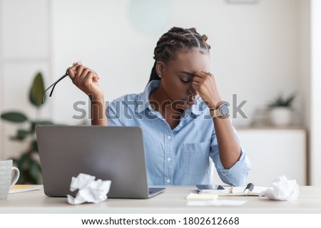 Deadline Stress. Overworked Black Female Entrepreneur Massaging Nosebridge At Workplace In Office, Exhausted After Using Laptop