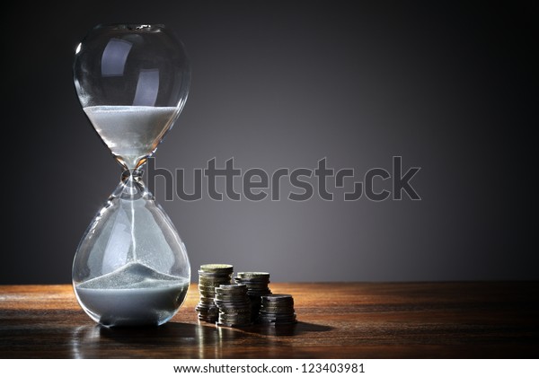 Deadline and time is money concept with\
hourglass and British coin\
currency