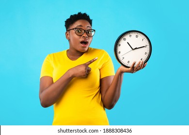 Deadline, Time Is Over. Oversized African Woman Showing Clock Posing Standing Over Blue Studio Background, Looking At Camera. Shocked Black Lady Being Late. Time's Tickling Concept