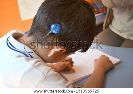Deaf boy with cochlear implant studying 