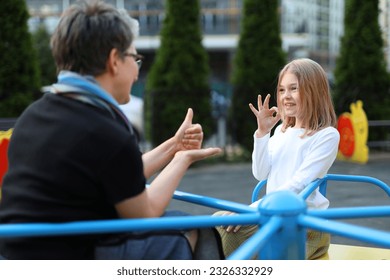 A deaf girl speaks sign language With a teacher on the playground. - Powered by Shutterstock