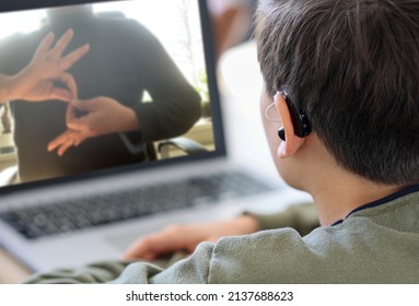 Deaf Teenager Boy Wearing Hearing Aid Using Laptop. Disable Student With Disabilities Deafness Distancing Learning Online From Home Making Communication Hands Language With Teacher Via VDO Call.