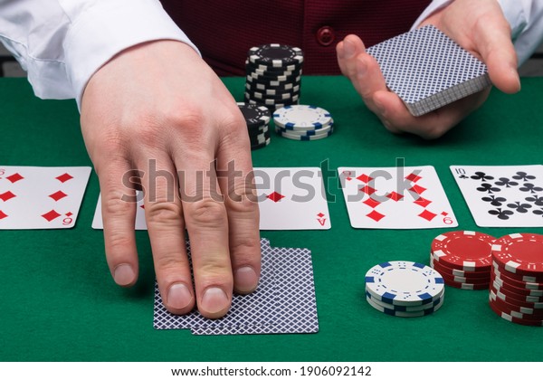 the dealer at the green poker table deals cards to\
the player
