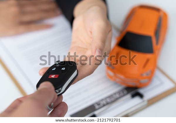 Dealer handing keys to new\
owners. Car sales business. Buying contracts. Customer and sales\
team cooperation concept after agreement Successful car loan\
contracts