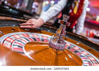 The dealer holds a ball and spins the roulette wheel in a casino.