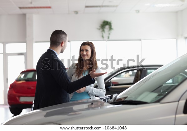 Dealer speaking to a\
woman in a dealership