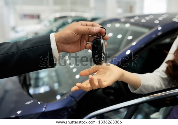 Dealership salesman giving electronic car keys\
to female customer