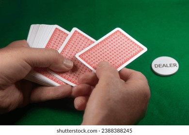 Dealing cards with the dealer button on a green baize covered table. Red coated classic playing cards - Powered by Shutterstock