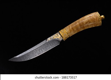 Dear adorned with gold dagger of Damascus steel on a black background