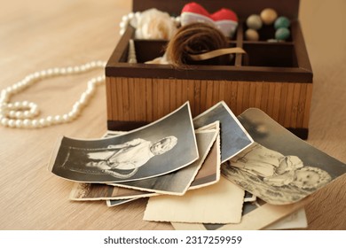 dear to heart memorabilia in an old wooden box, a stack of retro photos, a wooden rosary, vintage photographs of 1960, concept of family tree, genealogy, childhood memories